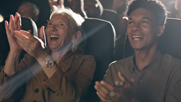 two people in an audience clapping and smiling